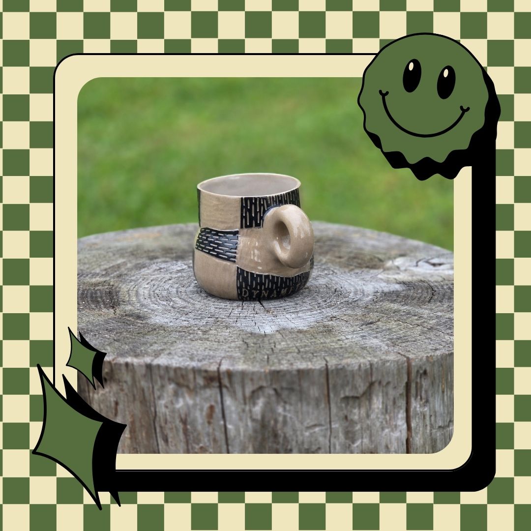Ceramic mug on a wooden stump with a checkered border and smiley face corner