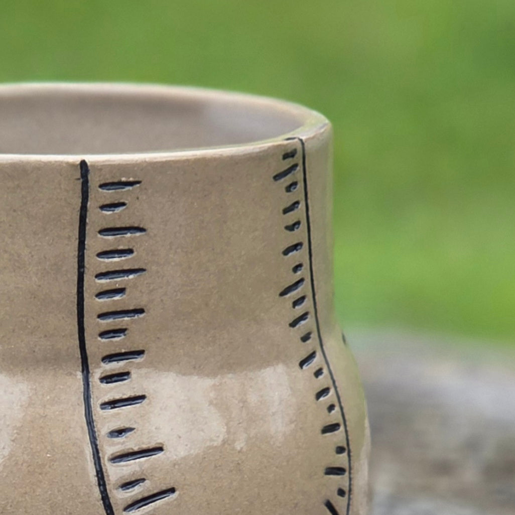 Close up detail shot of black line designs on ceramic cup.