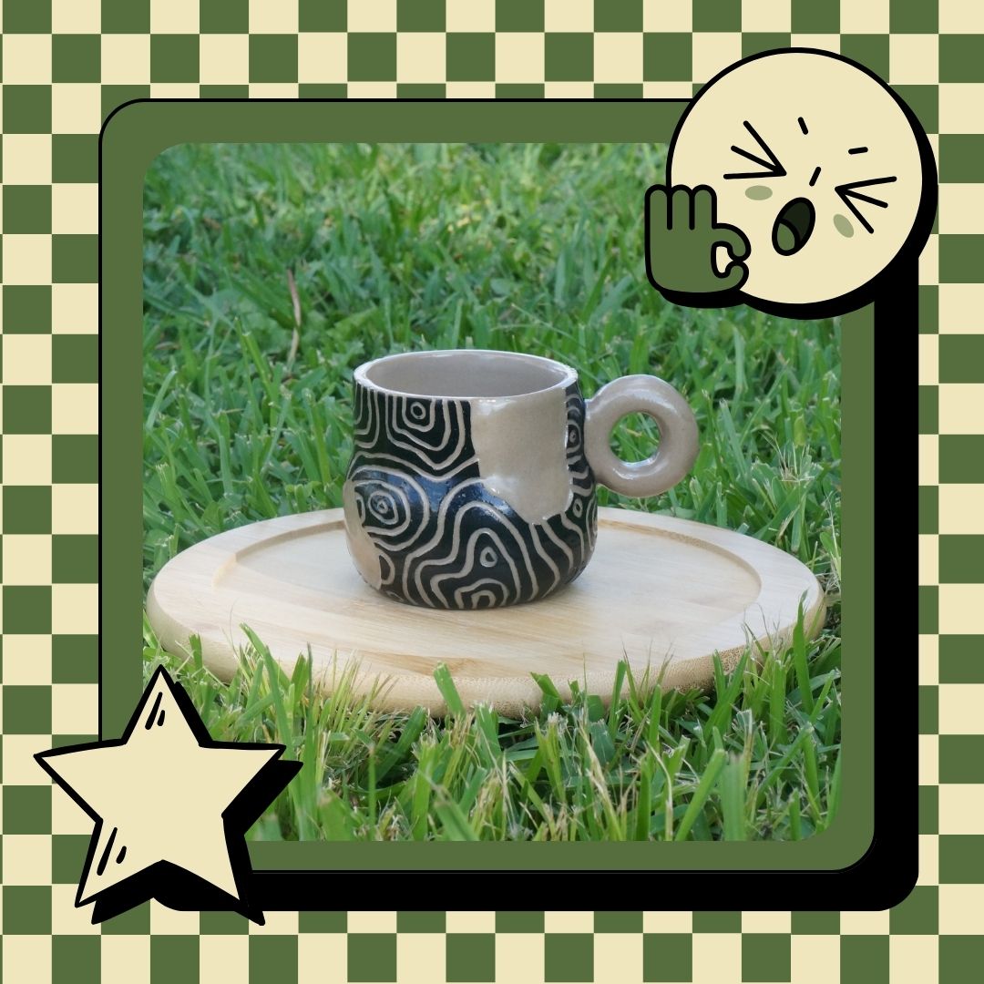 Ceramic mug with black spiral pattern on a wooden stand outdoors.
