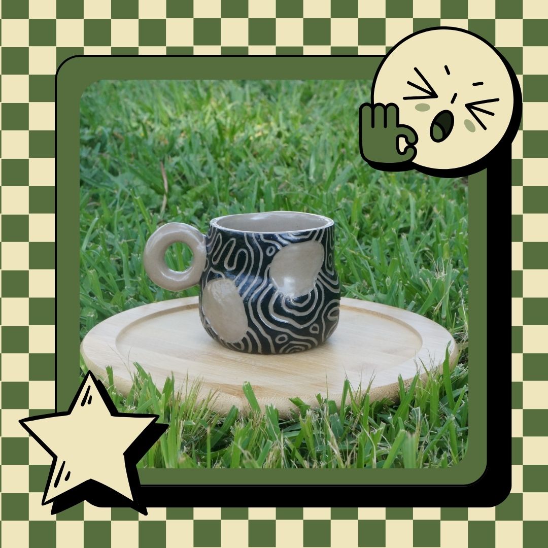 Ceramic mug with black and white pattern on a wooden stand outdoors