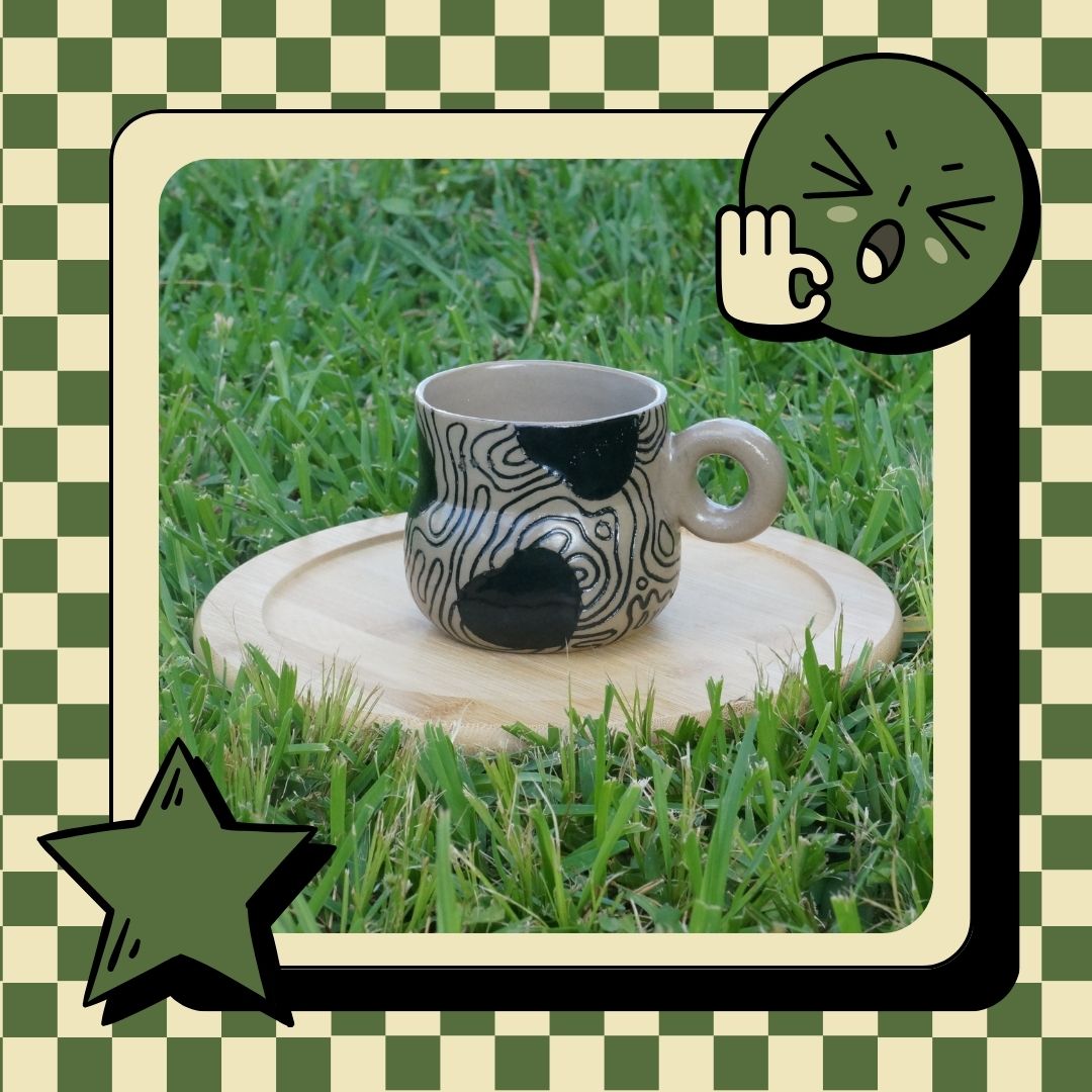 Ceramic mug with black abstract design on a grassy background