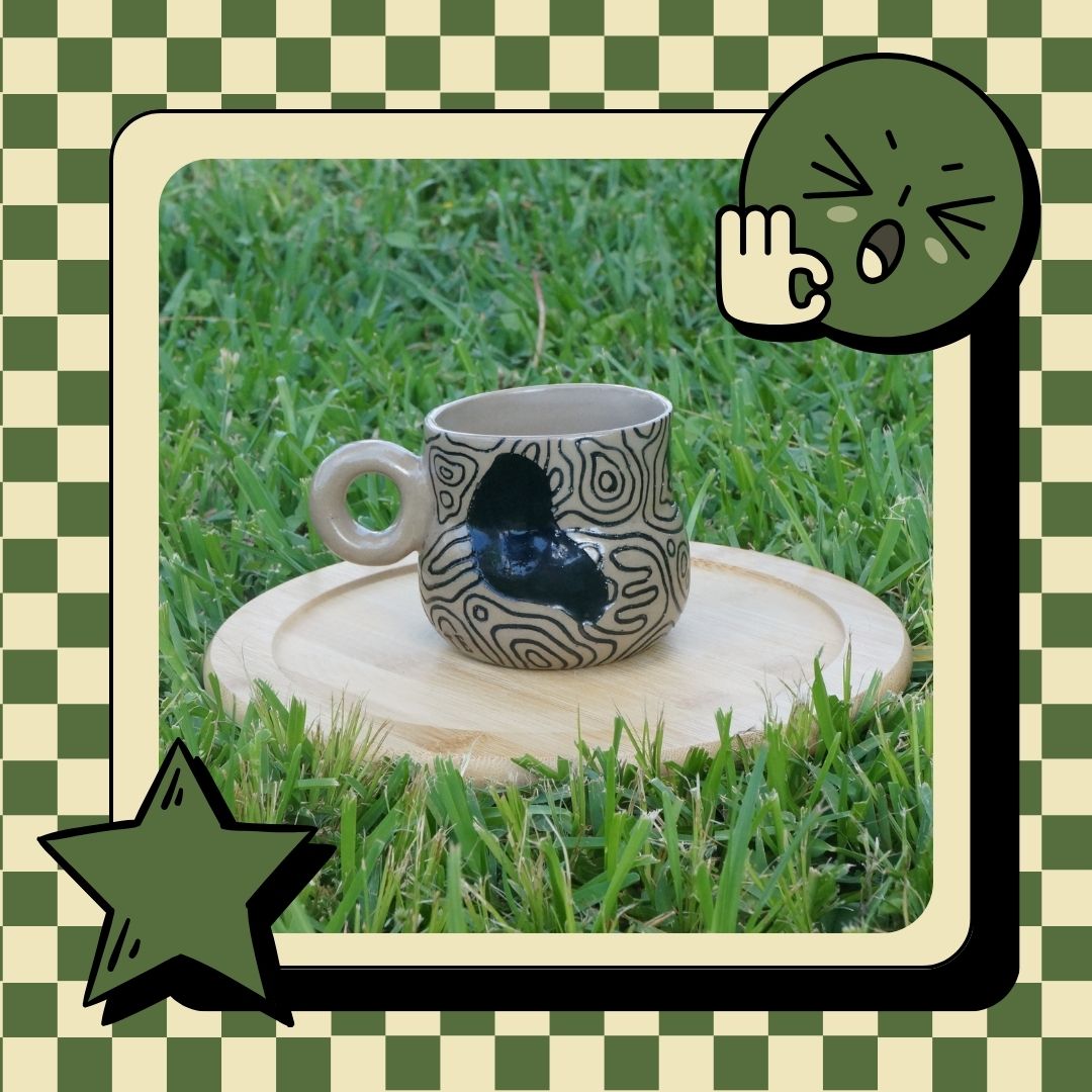 Decorative cup with black patterns on a grassy background, framed by cartoon elements.