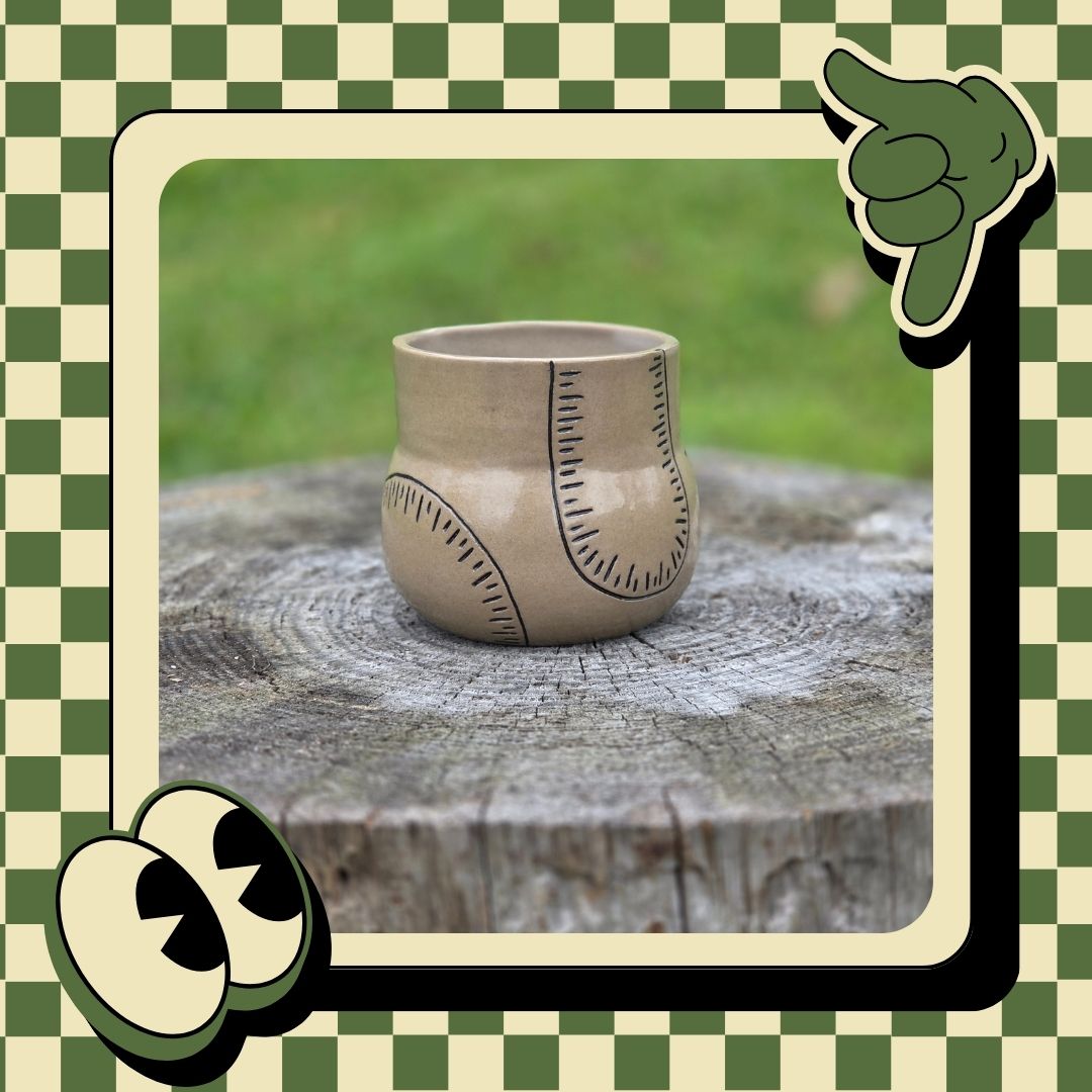 Ceramic cup with decorative lines on a wooden stump against a green checkered background